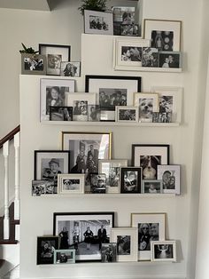 a bunch of pictures are hanging on the wall above a stair case in a house