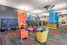 the interior of a children's library with brightly colored chairs and tables