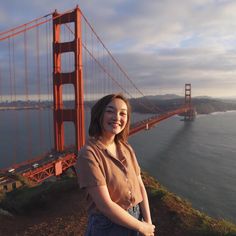 a woman standing in front of the golden gate bridge with her hands on her hips