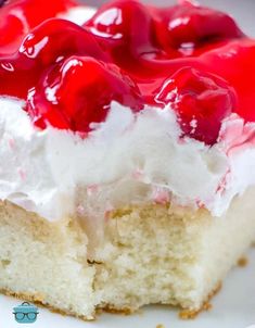 a piece of cake with white frosting and cherries on top is sitting on a plate