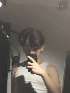 a woman taking a selfie in the mirror with her cell phone while wearing a tank top