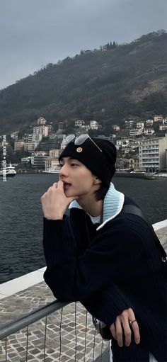 a young man leaning on a railing near the water