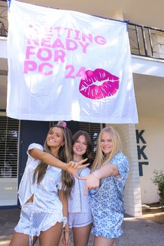 three girls standing in front of a white banner