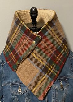 a blue jean jacket with a multicolored plaid scarf on it's collar