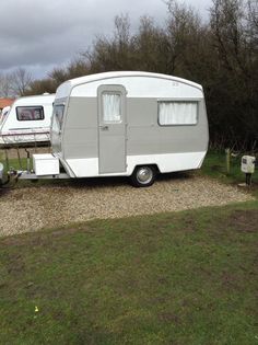 an rv parked next to another trailer in a field