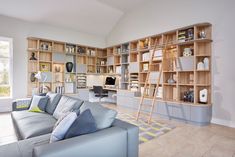 a living room filled with furniture and lots of bookshelves on the wall next to a window