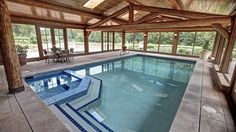 an indoor swimming pool in a house with wood ceilinging and windows on the side