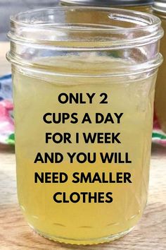 two jars filled with yellow liquid sitting on top of a wooden table