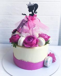 a cake decorated with pink flowers and a little princess figure on top is sitting on a white plate