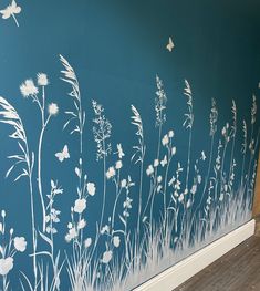 the wall is painted with white flowers and grass on blue walls, along with wood flooring