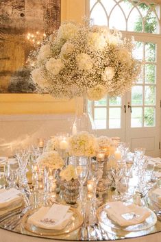 a table set with white flowers and candles