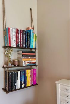 a book shelf filled with books next to a white dresser