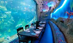 a restaurant with an aquarium in the background and tables set up for two people to eat