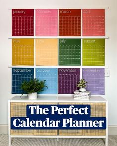 a colorful calendar is on the wall behind a white sideboard with wicker drawers