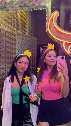 two young women taking a selfie in front of a neon sign with stars on it