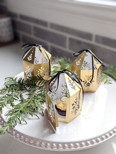 three gold and white boxes on a plate