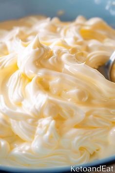 a bowl filled with whipped cream on top of a wooden table next to a spoon