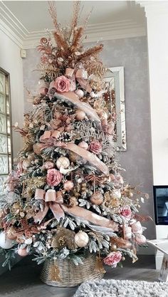 a decorated christmas tree in a living room with pink flowers and ribbons on the top