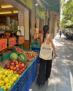 a woman is walking down the street by some fruit