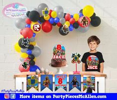 a young boy standing in front of a table with a cake and balloons on it