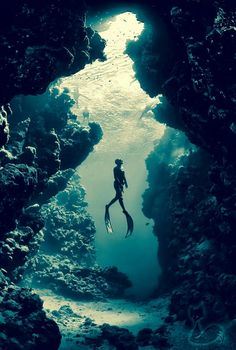 a person swimming in the water through a cave