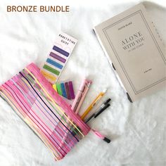 some pens and markers are laying on a blanket next to the book bronzee bundle