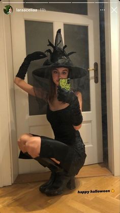 a woman dressed up as a witch holding a cell phone in her hand and sitting on the floor