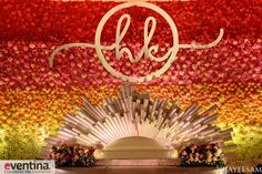 an elaborately decorated stage with flowers and a monogrammed sign