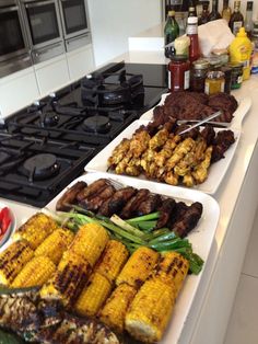 several trays of food sitting on top of a kitchen counter next to an oven