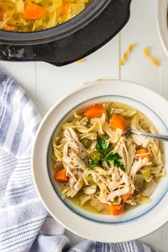 two bowls of chicken noodle soup on a white table