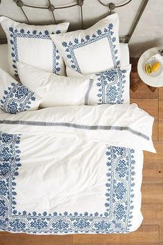 a bed with white and blue comforters on top of it