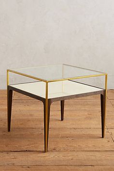 a glass and brass coffee table on wooden floor