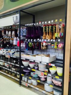 the shelves are full of bowls and utensils for sale at the store's counter