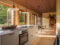 an open kitchen and dining area with wood ceilinging, large windows, and white cabinets