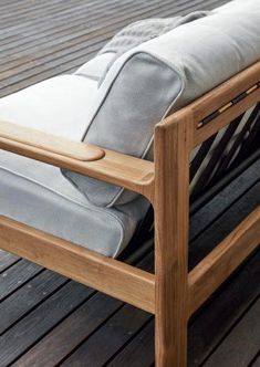 a wooden bench sitting on top of a wooden floor next to a white cushion and pillow