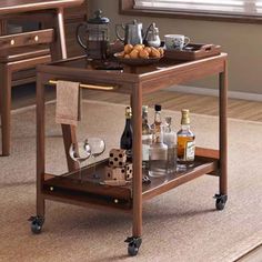 a wooden serving cart with two trays on wheels holding drinks and condiments