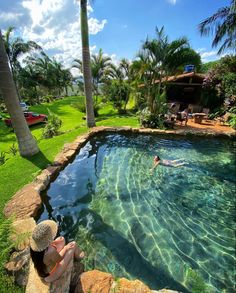 a person laying on the edge of a swimming pool with palm trees in the background