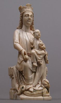 a statue of a woman holding a baby in her lap and wearing a crown on top of it