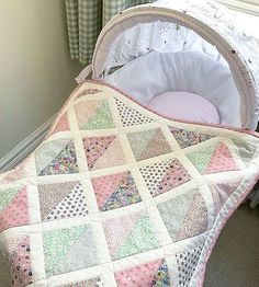 a baby crib with a pink and white quilt on it's side next to a window