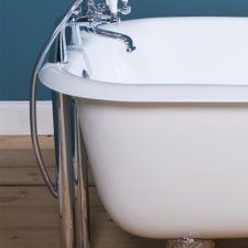 a white bath tub sitting on top of a wooden floor next to a blue wall