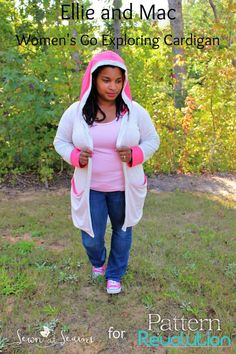 a woman wearing a pink and white hoodie standing in the grass with her hands on her hips