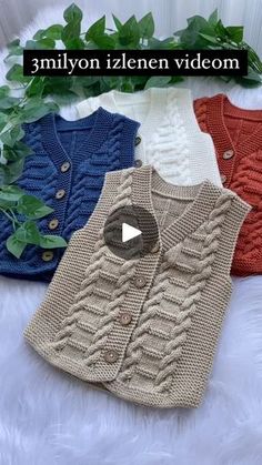 three sweaters with buttons on them sitting next to a plant