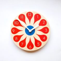 a red and white clock with blue numbers on it's face is shown against a white background