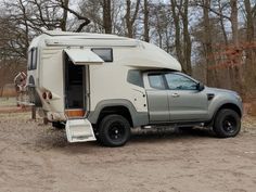 an off - road camper parked in the woods with its door open and snow plow attached to it