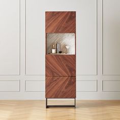 a wooden cabinet sitting on top of a hard wood floor next to a white wall