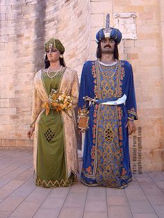 two people dressed in medieval clothing standing next to each other on a brick floored area