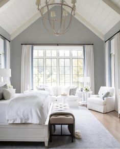 a large bedroom with white furniture and windows