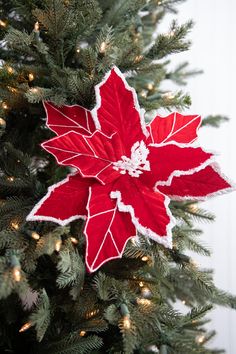 a red poinsettia ornament hanging from a christmas tree