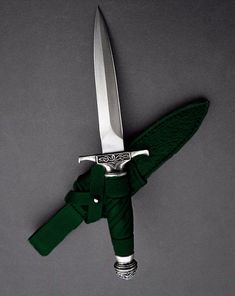 a knife with a green cloth wrapped around it's blade on a gray background