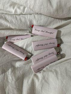 four batteries with writing on them laying on a bed covered in white sheets and linens